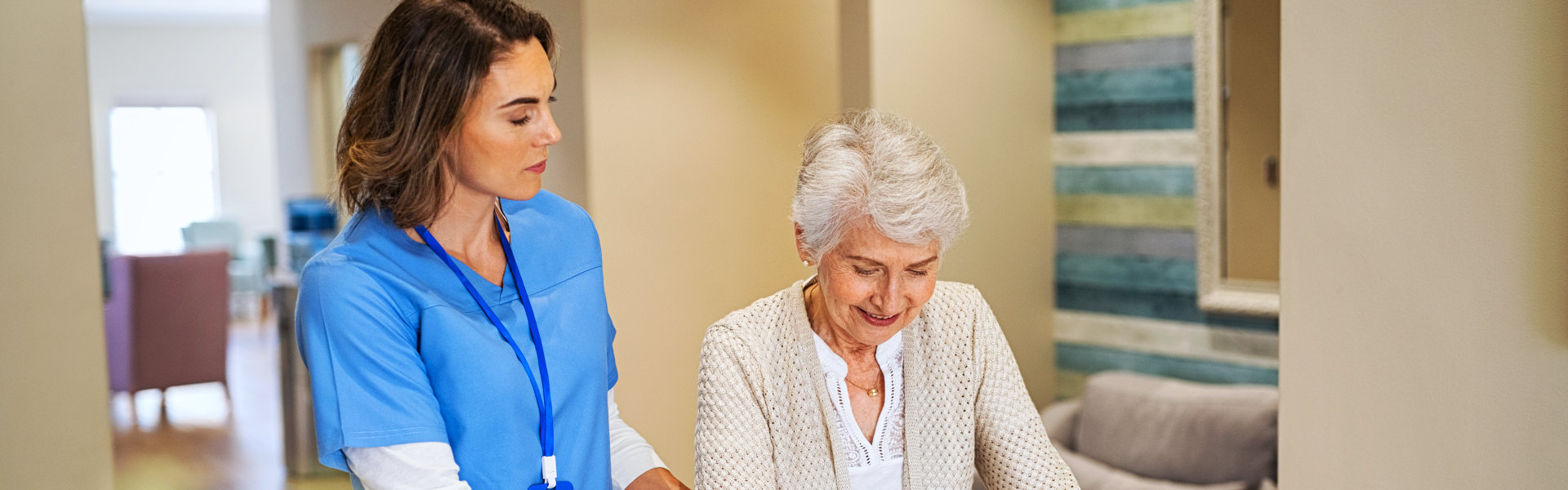 nurse assisting an elderly woman in walking