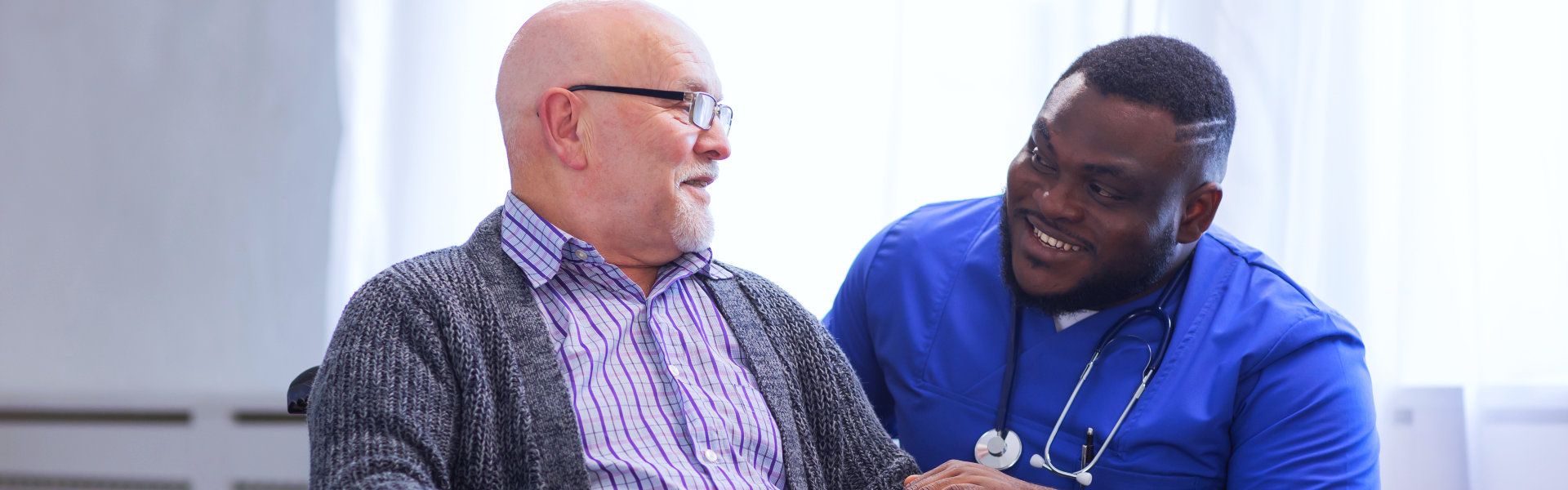 nurse and elderly man smiling at each other